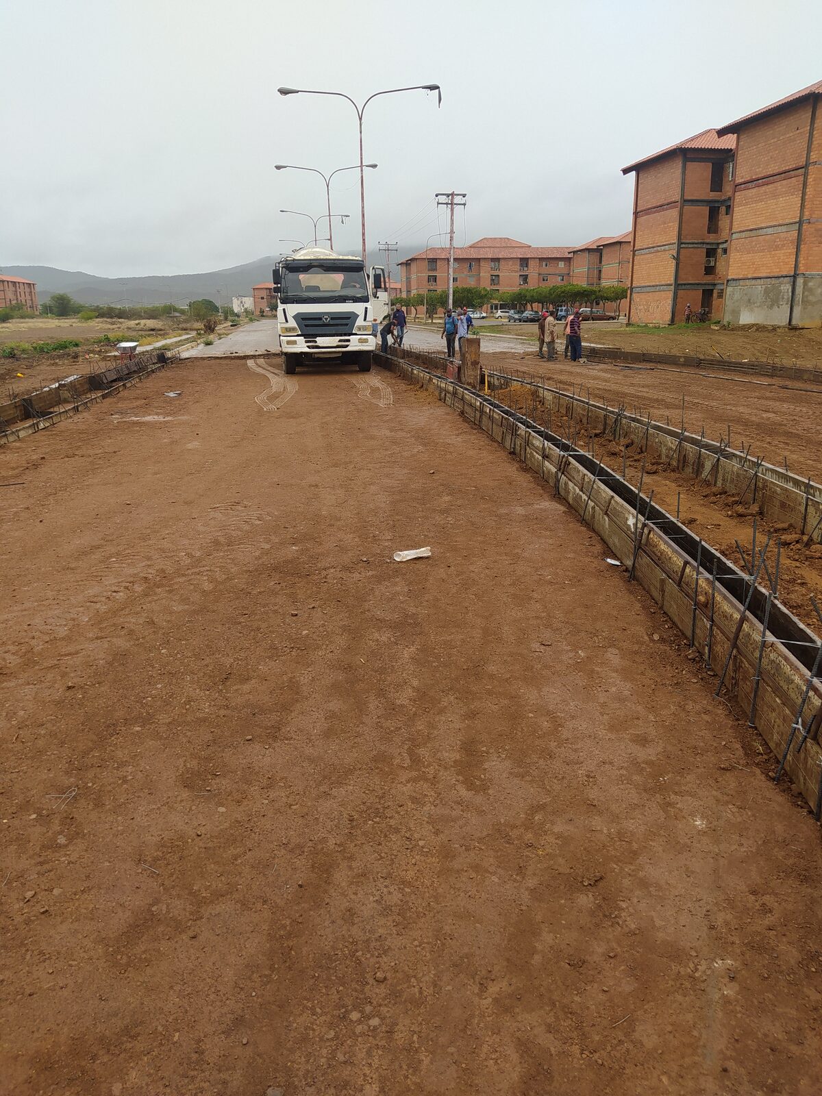 Camión mezclador y armadura de acero preparada para el vaciado de la estructura vial