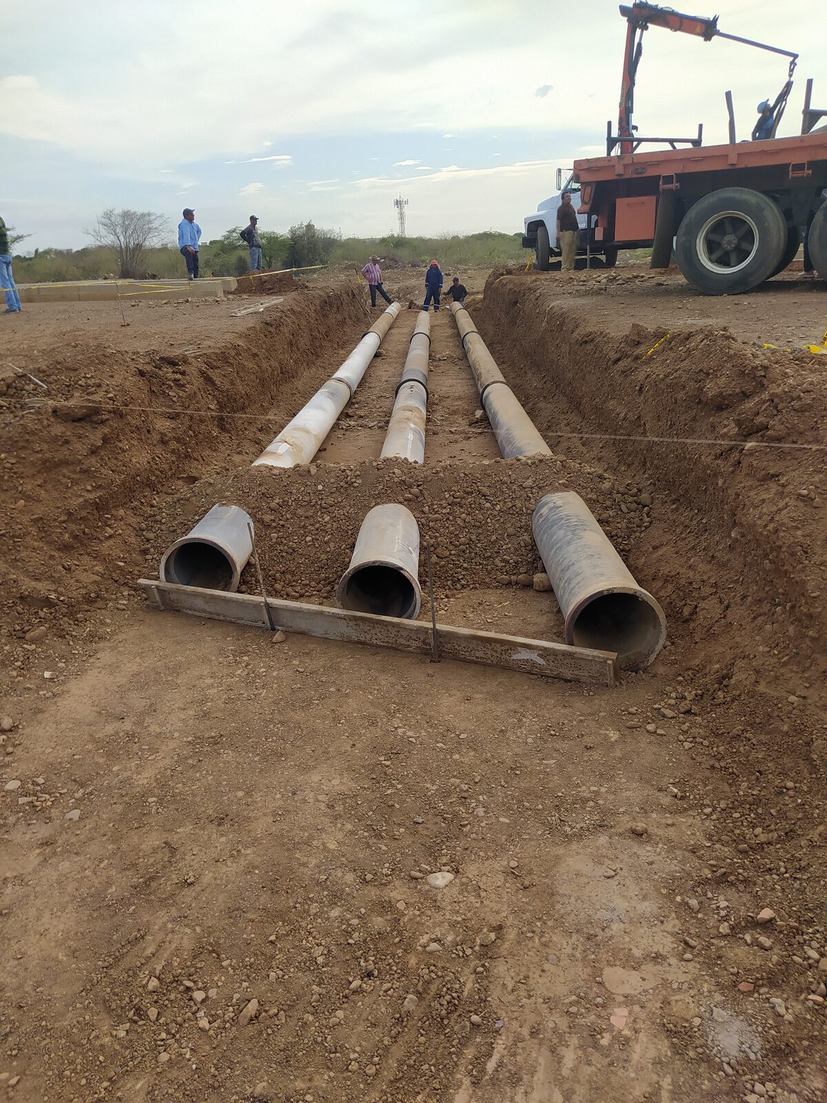 Instalación de tubería de concreto para drenaje en zanja durante la obra vial